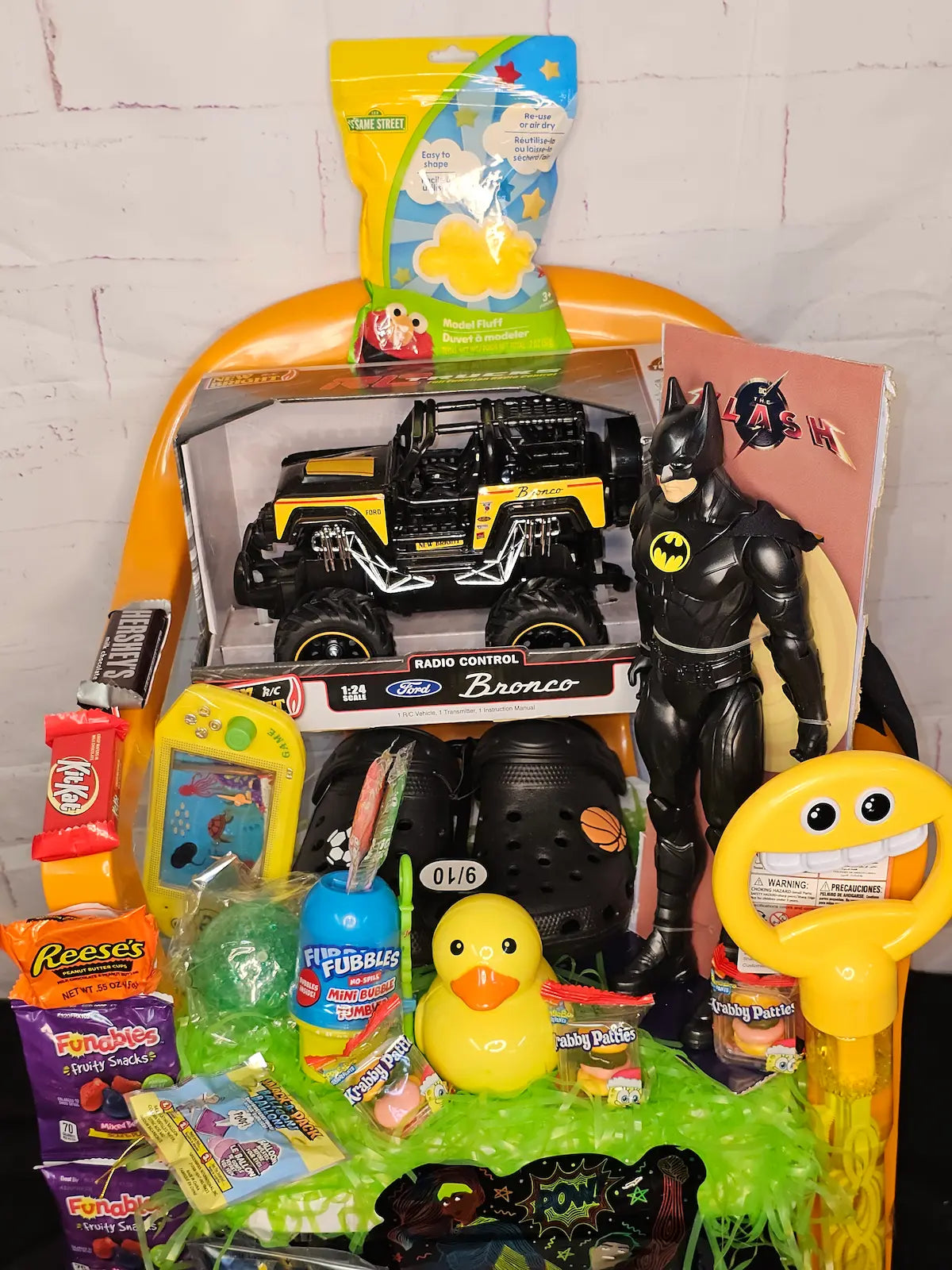Assorted toys and candy on a table with a white brick wall background